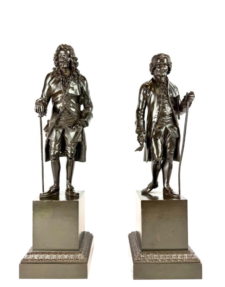 A pair of bronze sculptures of Voltaire and Rousseau.
