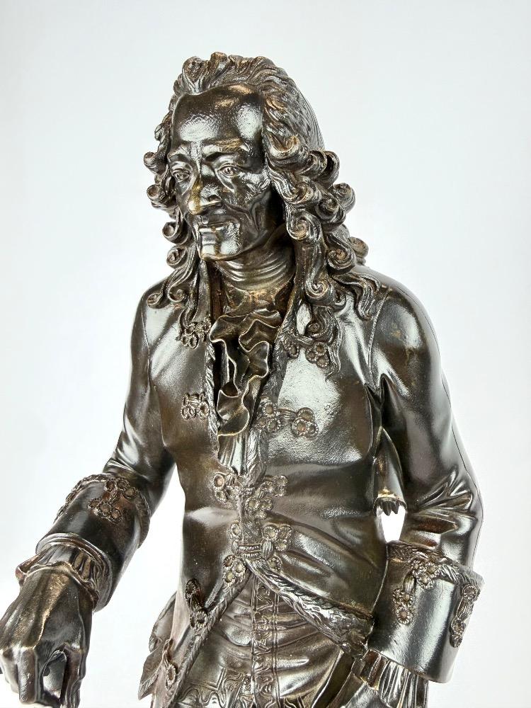 A pair of bronze sculptures of Voltaire and Rousseau.