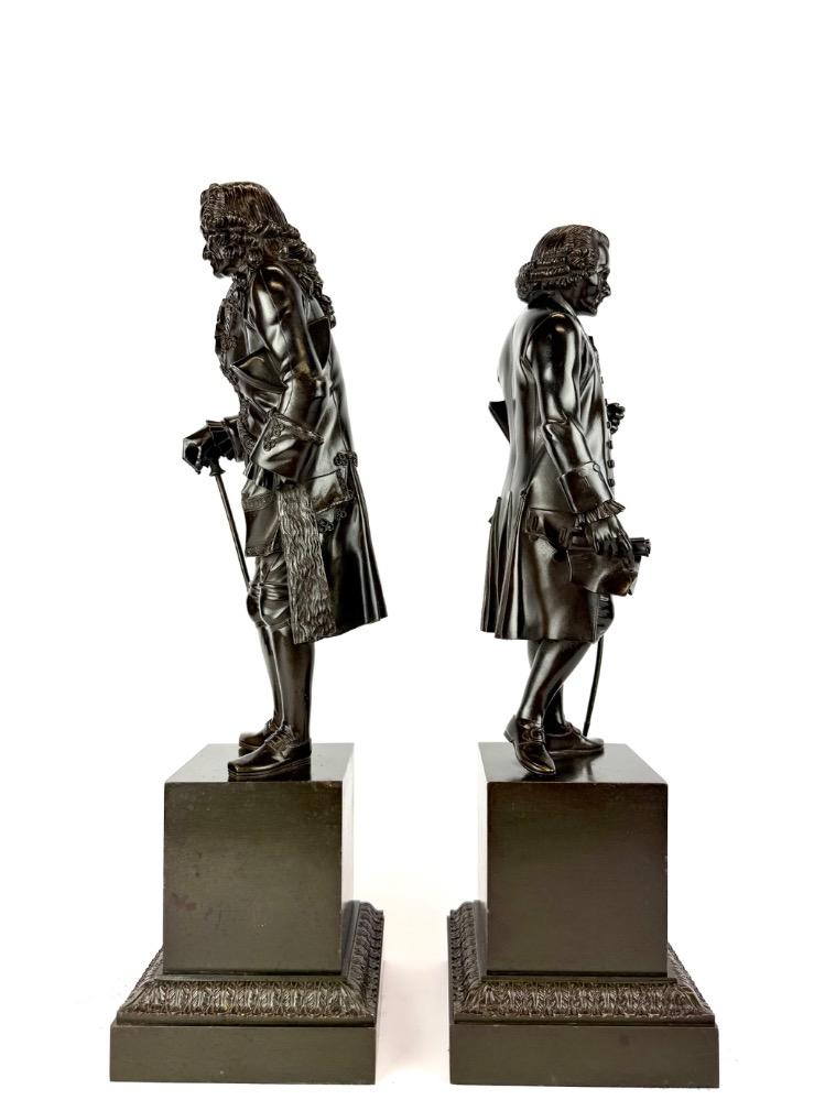 A pair of bronze sculptures of Voltaire and Rousseau.