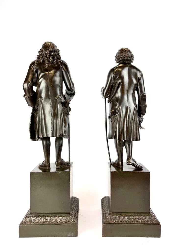 A pair of bronze sculptures of Voltaire and Rousseau.