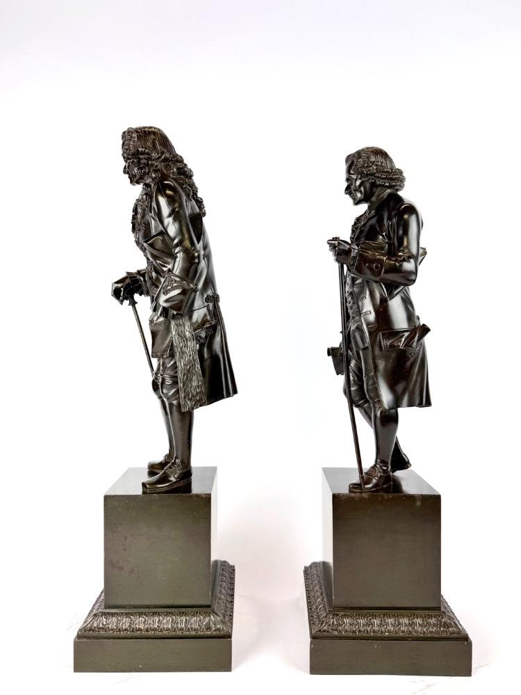 A pair of bronze sculptures of Voltaire and Rousseau.