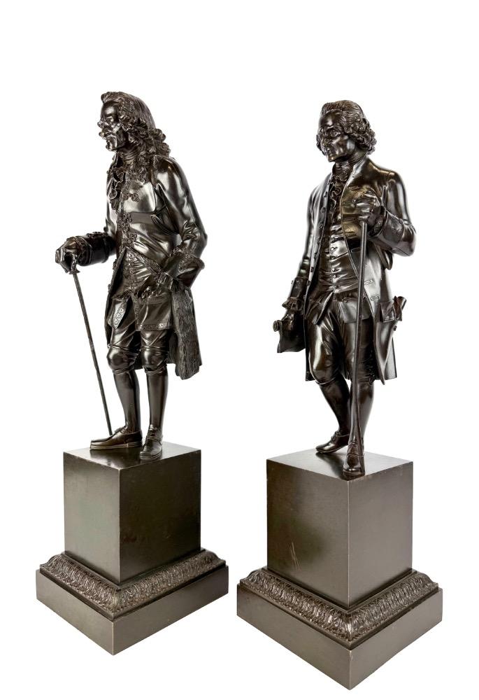 A pair of bronze sculptures of Voltaire and Rousseau.